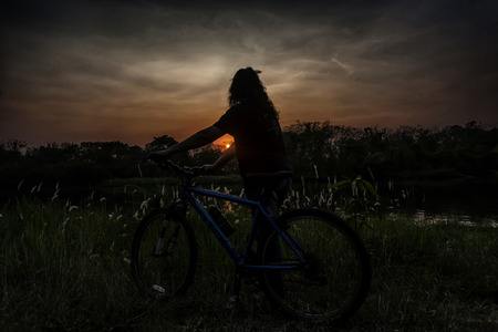 Girl with bicycle in the sunsetの写真素材