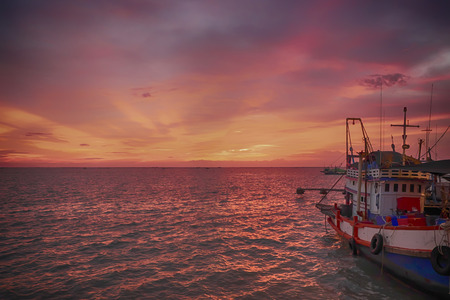 Last sunset and fishing boat in the sea 