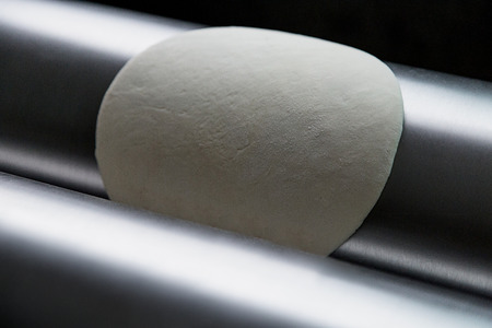 making pizza dough with machine for rolling doughの写真素材