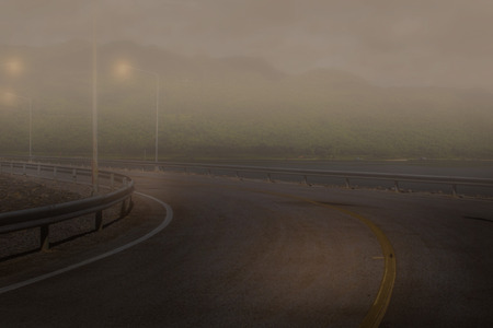 Road on a foggy in a brightness morning beside the lakeの写真素材