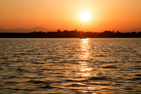 Silhouette of a boat running in the evening lakeの写真素材