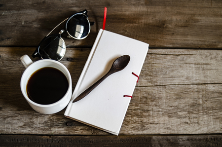 Wood desk with books and sunglasses still life work space and hot coffeeの写真素材