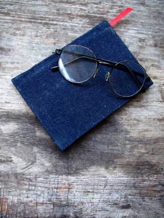 Notebook and eyeglasses on old wooden table, vintage style