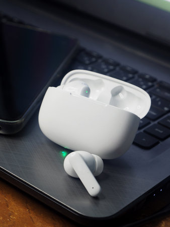Wireless earphones on a laptop keyboard, close-up.