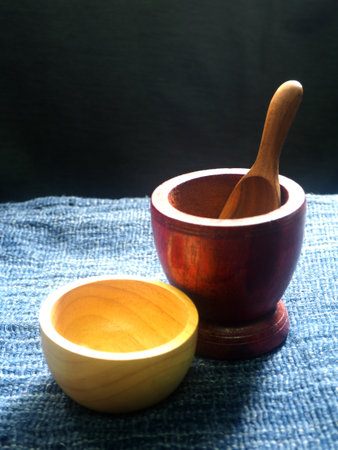 Wooden mortar and pestle on blue fabric background. Selective focus.