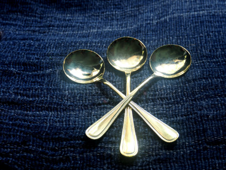 Three spoons on a blue fabric background. Selective focus.