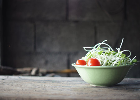 Fresh green sprouts in a bowl on a wooden table, selective focusの写真素材