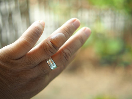 Hand of a man holding a ring in front of a blurred background