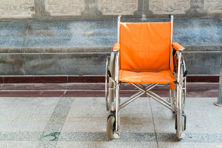 Orange empty wheelchair on the floor in temple areaの写真素材