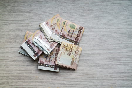 Stack of thousand bath Thai money on wooden table with copy space