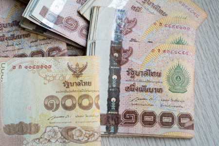 Stack of thousand bath Thai money on wooden table