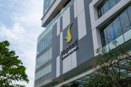 Vinpearl Beachfront Nha Trang hotel exterior with modern architecture, glass facade, and lush tropical foliage under an overcast sky. Nha Trang, 26.11.2025, Vietnamのeditorial素材