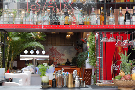 Vibrant outdoor bar scene with a well-stocked liquor shelf, neon signs, beer taps, fresh tropical fruits, and cocktail-making tools, inviting customers for refreshing drinks in a lively atmosphere. Nha Trang, 26.11.2025, Vietnamのeditorial素材