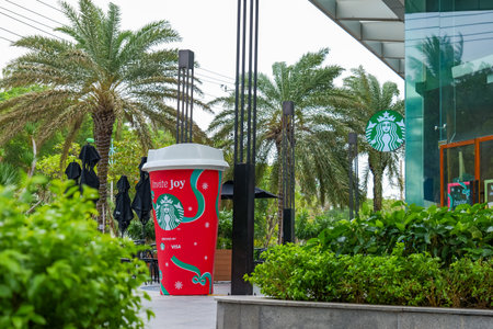 Giant Starbucks "Invite Joy" holiday cup display with palm trees and a modern building, celebrating festive season promotions. Nha Trang, 26.11.2025, Vietnamのeditorial素材