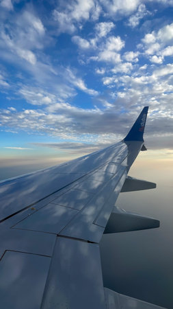 Airplane wing view above the clouds under bright blue sky Dubai 18.01.2025 United Arab Emirates.のeditorial素材