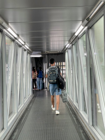 Traveler carrying backpack and luggage walking through boarding tunnel, Dubai 18.01.2025 United Arab Emirates.のeditorial素材