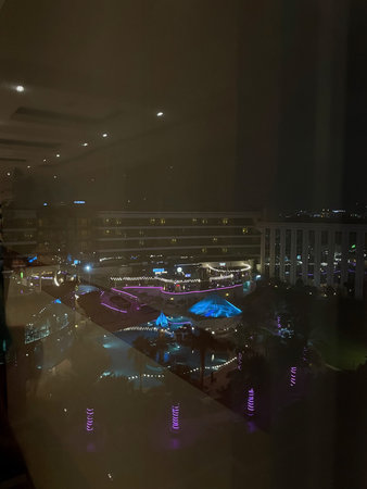 Hotel courtyard with pool and colorful night lighting viewed from window, Dubai 18.01.2025 United Arab Emirates.のeditorial素材