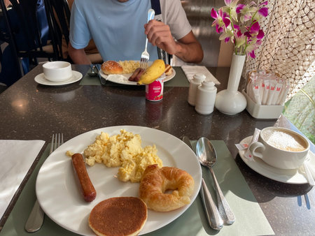 Hotel Dubai Connect. Table with breakfast of eggs, croissant, sausage and coffee in hotel restaurant, Dubai 18.01.2025 United Arab Emirates.のeditorial素材
