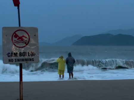 Stormy sea with waves crashing near safety sign on empty beach in Nha Trang, 06.11.2025, Vietnam.のeditorial素材