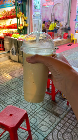 Hand Holding Fruit Smoothie in Plastic Cup at a Vibrant Street Market in Vietnam Nha Trang 26.10.2025 Vietnamのeditorial素材