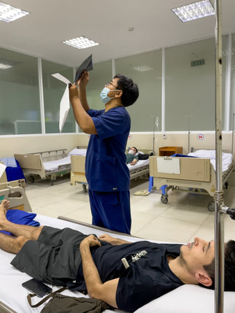 Doctor examining X-ray image near hospital bed, Nha Trang 18.10.2025 Vietnamのeditorial素材