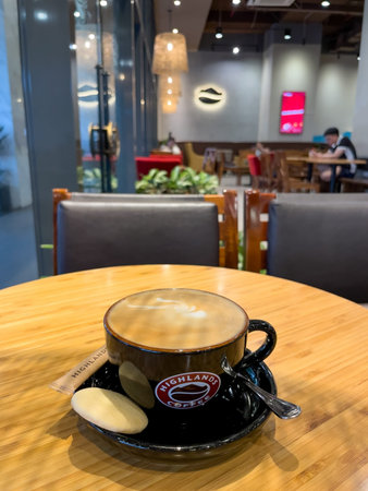Cup of coffee on wooden table inside Highlands Coffee cafe. Nha Trang, October 10, 2025, Vietnam.のeditorial素材