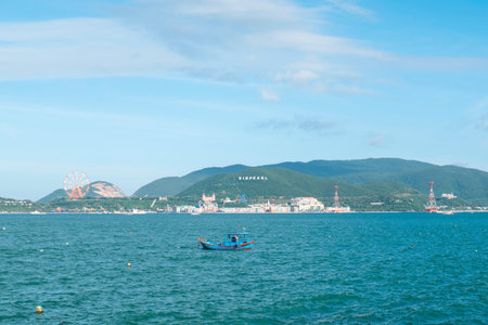 Traditional Blue Fishing Boat in Nha Trang Bay Vietnam with Vinpearl Resort Skyline, Bright Coastal Travel Landscape, Cinematic Horizon and Copy Space Nha Trang 20.12.2025 Vietnamのeditorial素材