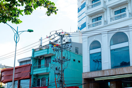 Authentic Urban Street Scene in Vietnam featuring Colorful Architecture and Complex Overhead Power Lines with Cinematic Daylight and Clear Blue Sky Nha Trang 20.12.2025 Vietnamのeditorial素材