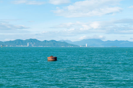 Scenic Coastal Landscape with Rusty Buoy Floating on Turquoise Sea under Cloudy Blue Sky with...