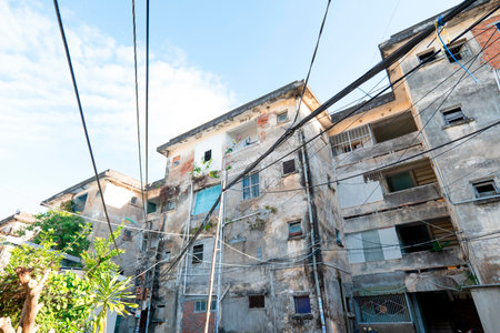 Low-angle shot of weathered vintage apartment buildings with tangled power lines under clear blue sky, capturing urban decay and authentic street architecture. Nha Trang 20.12.2025 Vietnamのeditorial素材