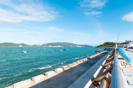 Sunny Coastal Promenade in Vietnam with Traditional Fishing Boats and Scenic Mountain View - Bright Daylight with Ample Sky Copy Space for Travel Nha Trang 20.12.2025 Vietnamのeditorial素材