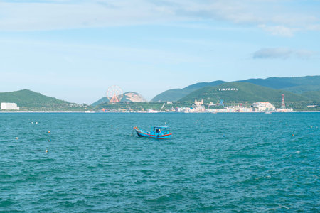 Traditional Blue Fishing Boat in Nha Trang Bay Vietnam with Vinpearl Island Coastline, Tropical Travel Landscape, Wide Angle Cinematic Daylight View Nha Trang 20.12.2025 Vietnamのeditorial素材