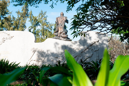 Ancient Chinese Warrior Statue Rear View Behind Stone Relief Wall with Cinematic Daylight and Lush Greenery Framing for Cultural Travel and Heritage Nha Trang 20.12.2025 Vietnamのeditorial素材