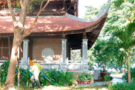 Traditional Vietnamese Pagoda Temple Architecture with Gardener Watering Lush Tropical Garden under Bright Sunlight and Cinematic Depth of Field Nha Trang 20.12.2025 Vietnamのeditorial素材