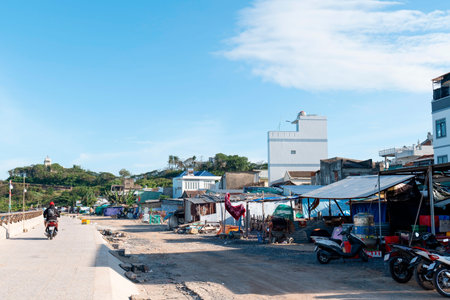 Authentic Coastal Village Scene in Southeast Asia with Motorbikes and Architecture under Bright Blue Sky, Wide Angle Daytime Landscape Photography Nha Trang 20.12.2025 Vietnamのeditorial素材