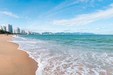 Panoramic City Beach View with Turquoise Ocean Waves and Modern Urban Skyline under a Bright Blue Sky with Copy Space for Travel Marketing Campaigns Nha Trang 20.12.2025 Vietnamのeditorial素材