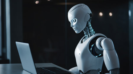 Robot humanoid working with laptop computer in modern office. 3D renderingの素材