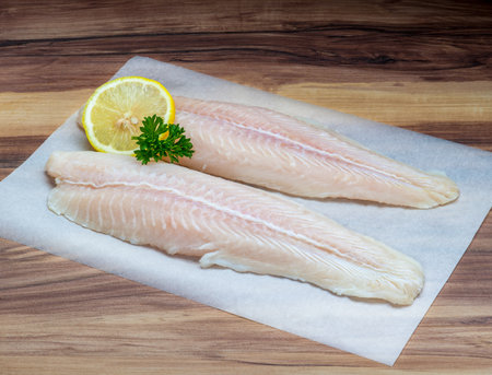 Fish fillet with lemon slice and parsley on wax paper
