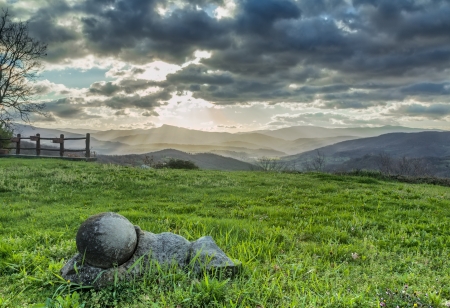 The sun s rays filter through the dark clouds in the morning panorama of the Tuscan hills の写真素材