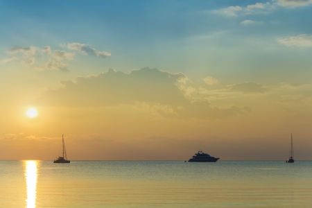 The summer sunset illuminates boats and yachts on the Sicilian coast.の写真素材