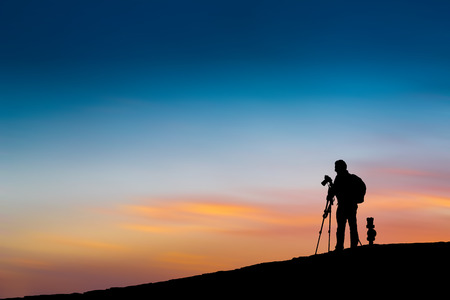 The passion of the photographer in a silhouette at sunsetの写真素材