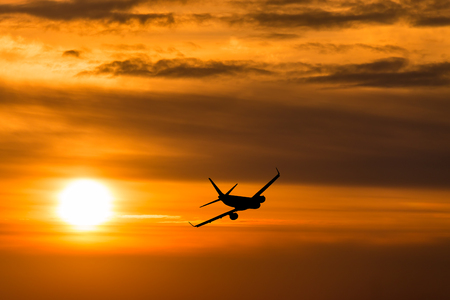A plane flying towards a beautiful sunsetの写真素材