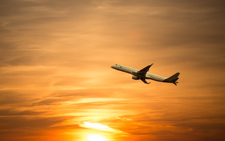 A plane flying towards a beautiful sunsetの写真素材