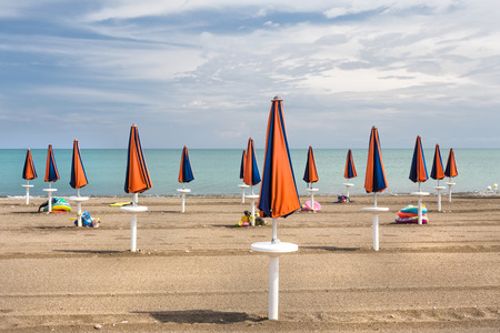 At the beginning and at the end of the bathing season the umbrellas are closed waiting for a few days of warm sunshine.の写真素材