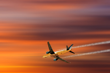 A plane flying towards a beautiful sunsetの写真素材