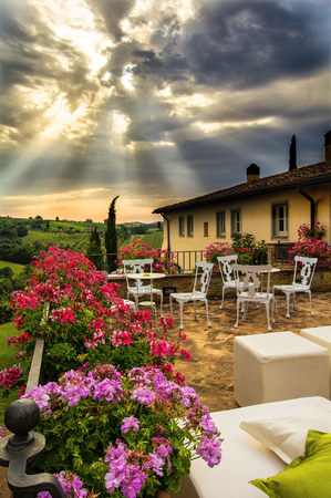Preparation of an event at a classic Tuscan villa illuminated by special rays of sunlight that cross the cloudsの写真素材