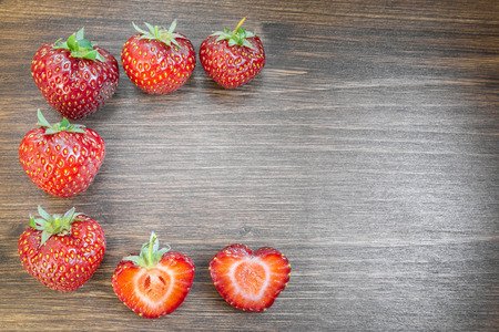 Strawberries on an old country table. With a strawberry cut in half that almost seems to form a heart. A typical summer fruit that is the season of love.の写真素材