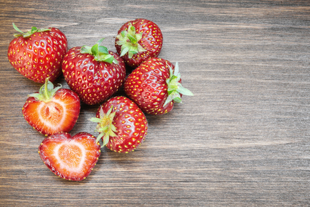 Strawberries on an old country table. With a strawberry cut in half that almost seems to form a heart. A typical summer fruit that is the season of love.の写真素材