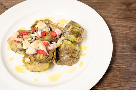 Roman artichokes in a pan with fresh Tropea onion, Sicilian chilli pepper all garnish with oil and lemon cream.の写真素材