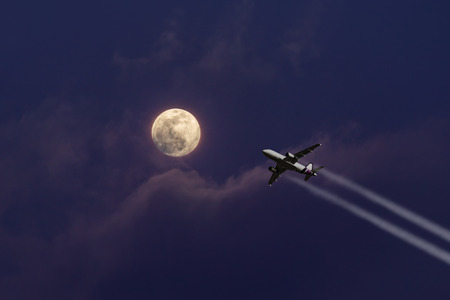A plane flying towards a beautiful moonlightの写真素材